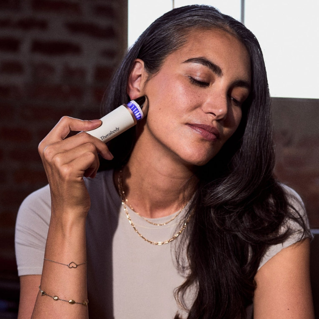 Woman using a depuffing wand to depuff and lymf drainage her face