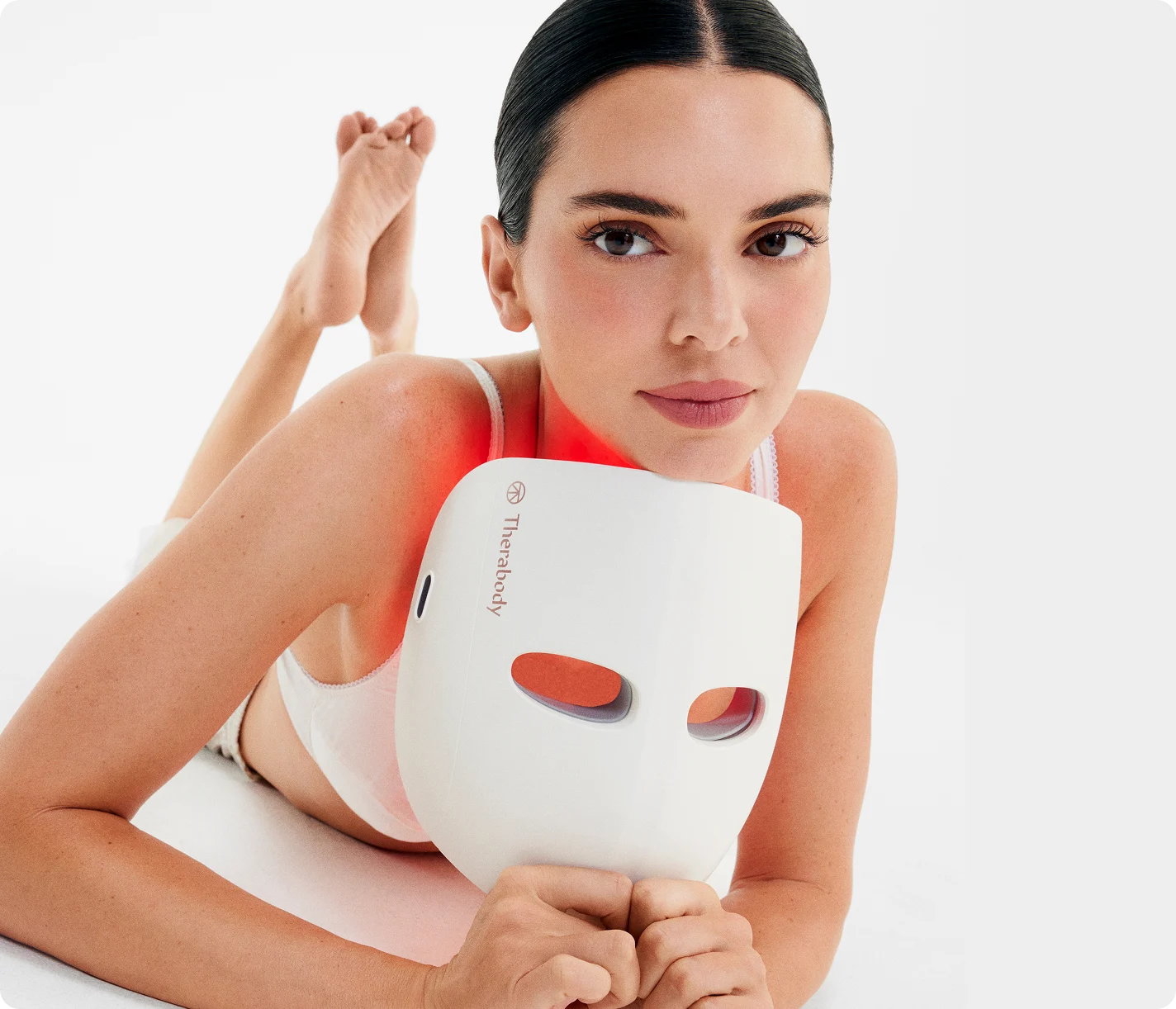 Kendall Jenner using a white LED face mask on a light background

